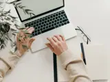 Handen typen op een laptop.